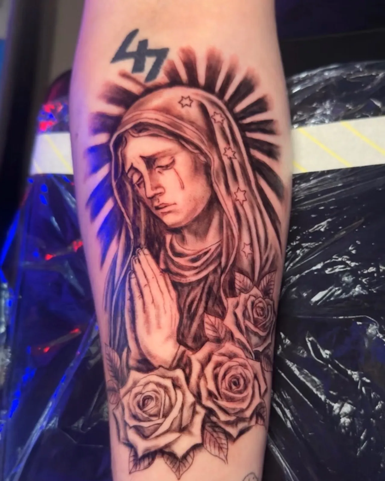 Black and grey Virgin Mary with praying hands and roses forearm tattoo by Slick at Studio AZ Tattoo Minneapolis