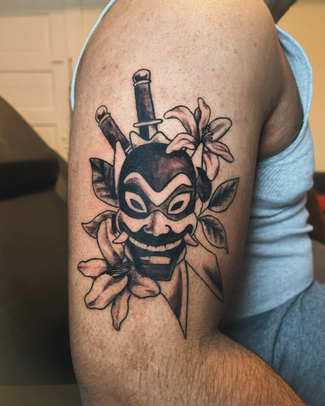 Black and grey hannya mask with daggers and lilies upper arm tattoo by Slick at Studio AZ Tattoo Minneapolis